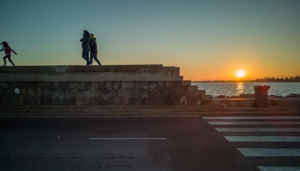 Burriana, Spain 12/06/18: Family strolling by jetty at sunset