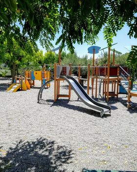 children playground with very colorful swings and some trees