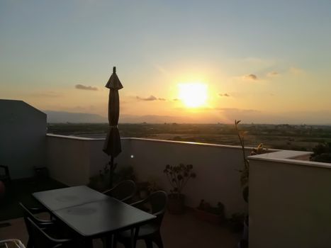Sunset over mountains seen from a terrace with a parasol