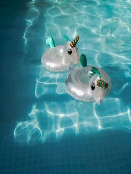 Floating coasters in the shape of unicorns in the water of a pool