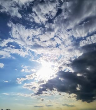 Storms clouds hiding the sun with reflections in the clouds and blue sky in the background