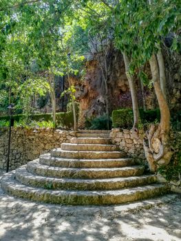 Round stone stairs in natural landscape with stone walls and trees