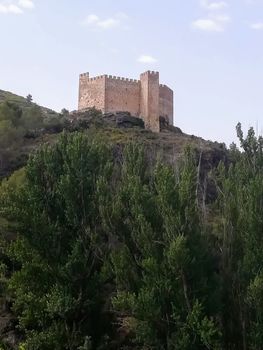 View of the ancient castle of Gaibiel with the forest below and the cloudy sky