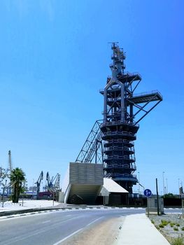 View of the old blast furnace exposed at a roundabout in the Port of Sagunto with the cranes of the commercial port in the background