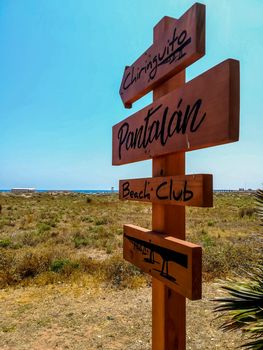 Wooden sign with arrows indicating the way to the beach of Puerto de Sagunto