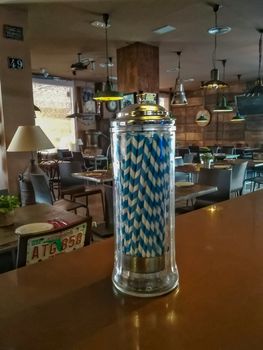 Pot of blue and white straws inside a bar with old lamps