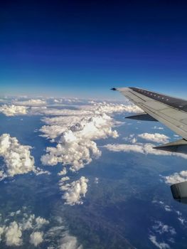 View of part of the wing and the sky with white clouds from an airplane