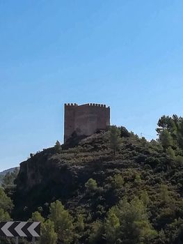 View of the ancient castle of Gaibiel with the forest below and the cloudy sky
