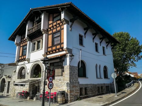 Nice white house with stone on the facade and roof with blue sky background