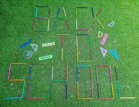 School material in composition on artificial grass background