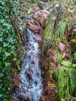 Small waterfall with reddish rocks and varied vegetation