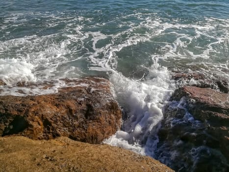View of the Mediterranean sea breaking against the rocks generating sea foam