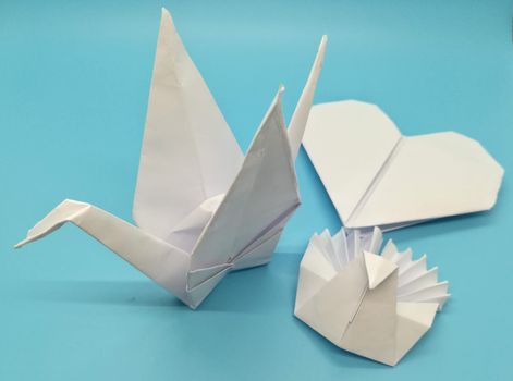 Origami figures made with white paper on blue background