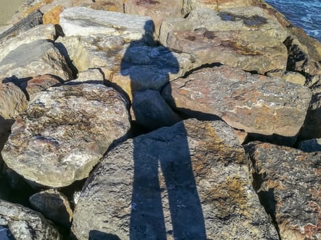 Shadow of spiky person on a breakwater in the Mediterranean Sea