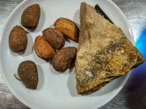 Almonds with natural stone opener on white plate