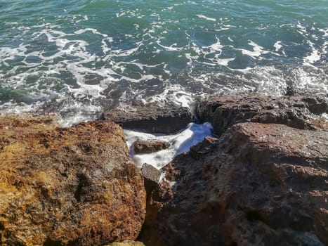 View of the Mediterranean sea breaking against the rocks generating sea foam