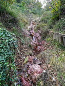Small torrent of water flowing through reddish rocks