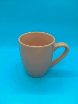 Pink ceramic coffee cup on blue background