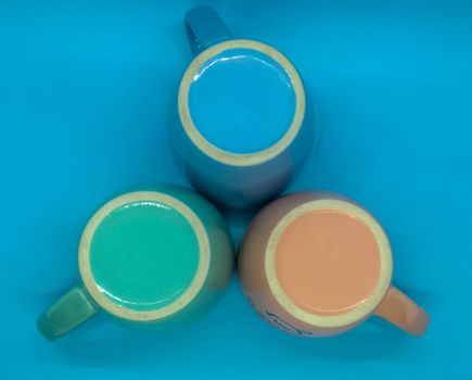 Colorful ceramic coffee cups on blue background