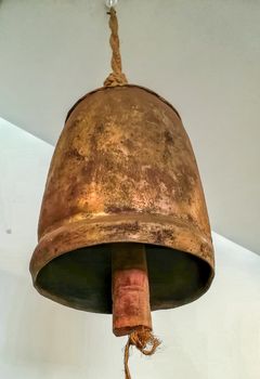 Old and rusty metal cowbell hanging from the ceiling