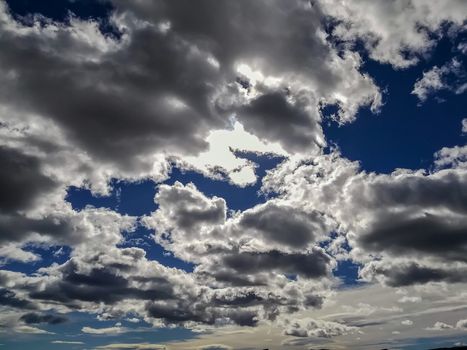 Sky with threatening storm clouds in various blue tones with sunlight through