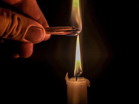 Matches burning to light a candle on black background