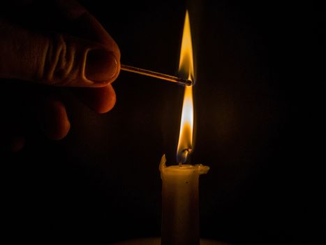 Matches burning to light a candle on black background