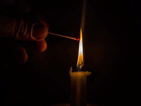 Matches burning to light a candle on black background