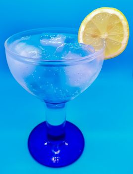 Gin and tonic with a slice of lemon on blue background