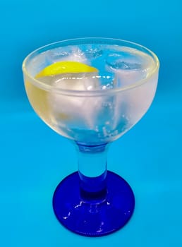 Gin and tonic with a slice of lemon on blue background