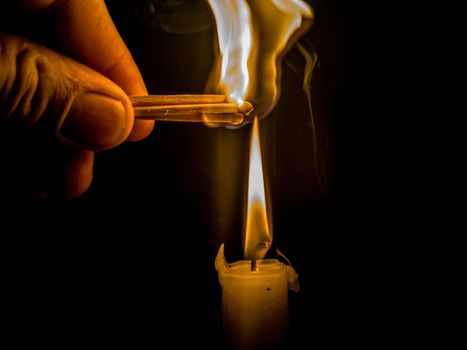 Matches burning to light a candle on black background