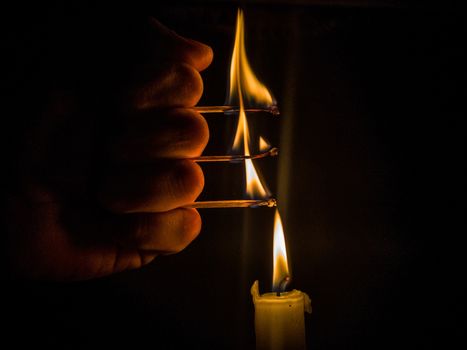 Matches burning to light a candle on black background