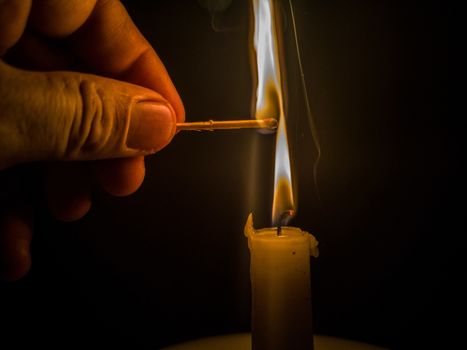 Matches burning to light a candle on black background