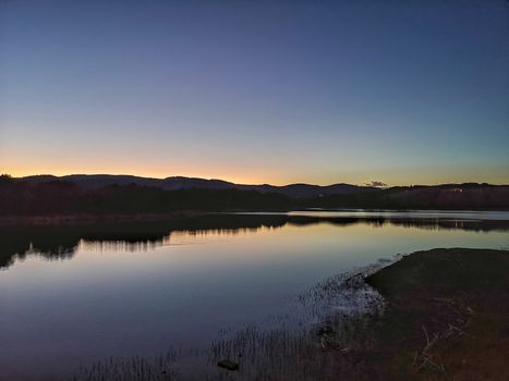 View of Puebla reservoir with mountains in the background and a pine forest