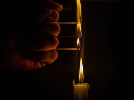 Matches burning to light a candle on black background