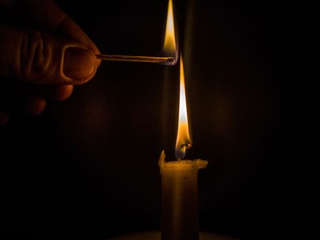 Matches burning to light a candle on black background