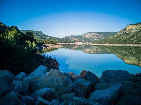 View of Puebla reservoir with mountains in the background and a pine forest