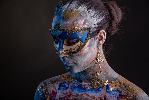 Portrait of a young masked woman with creative makeup on the theme of Venice Carnival