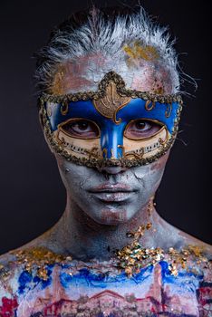 Portrait of a young masked woman with creative makeup on the theme of Venice Carnival