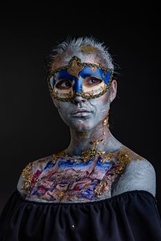 Portrait of a young masked woman with creative makeup on the theme of Venice Carnival