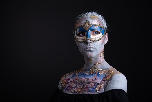 Portrait of a young masked woman with creative makeup on the theme of Venice Carnival