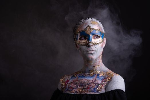 Portrait of a young masked woman with creative makeup on the theme of Venice Carnival