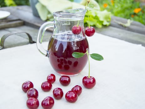 Cold cherry juice in jar and ripe berries, selective focus.