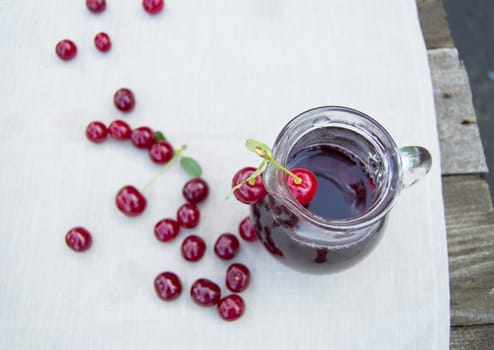 Cold cherry juice in jar and ripe berries, selective focus.