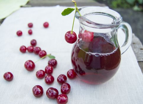 Cold cherry juice in jar and ripe berries, selective focus.