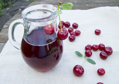 Cold cherry juice in jar and ripe berries, selective focus.