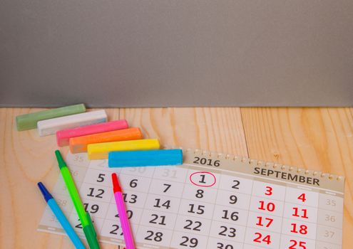 Back to school, calendar, colored chalk on wooden background.