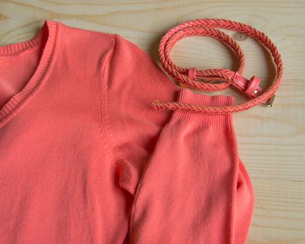 Women's fashion pink sweater with a belt on a light wooden background