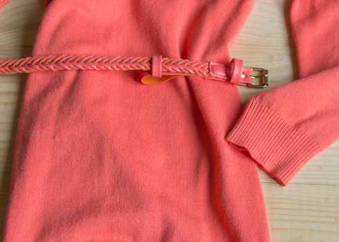 Women's fashion pink sweater with a belt on a light wooden background