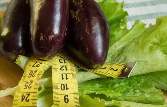 The concept of diet, healthy eating, lettuce eggplant measuring tape.